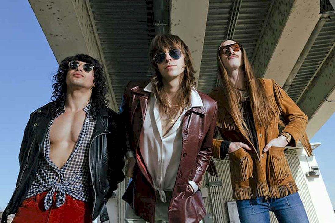 Cinema Stereo Photo Credit © Kate LaMendola - three men with long hair - one with open shirt, standing under a concrete structure