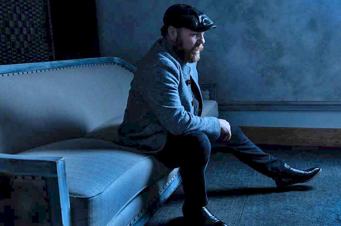 MARC BROUSSARD Chance Worth Taking Album Review - Photo Credit © Jeff Fasano - man seated on blue sofa wearing blue clothes and cap