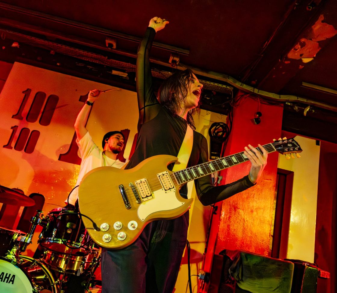 LAURA COX Live at the 100 Club London - photo credit Phil Honley. Girl holding cream coloured electric guitar with one hand