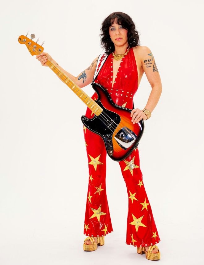 DANIELLE NICOLE Announces UK Fireflies Dates - Photo by Ben McBee - bass guitarist wearing red glam clothing holding guitar