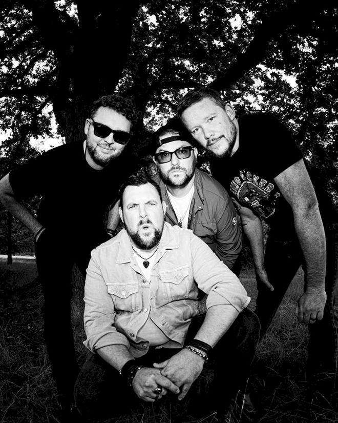 WOOD BURNT RED Hold On Tight - photo credit © Lucy Cave - four white men crouching. All four men have beards.