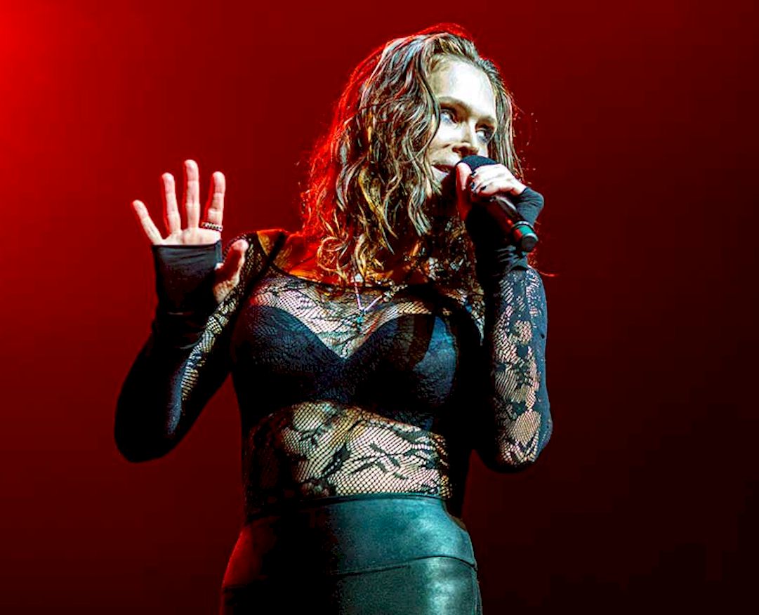 BETH HART UK Shows photo credit © Ali Burman - female singer on stage with microphone wearing lace top and leather-look jeans