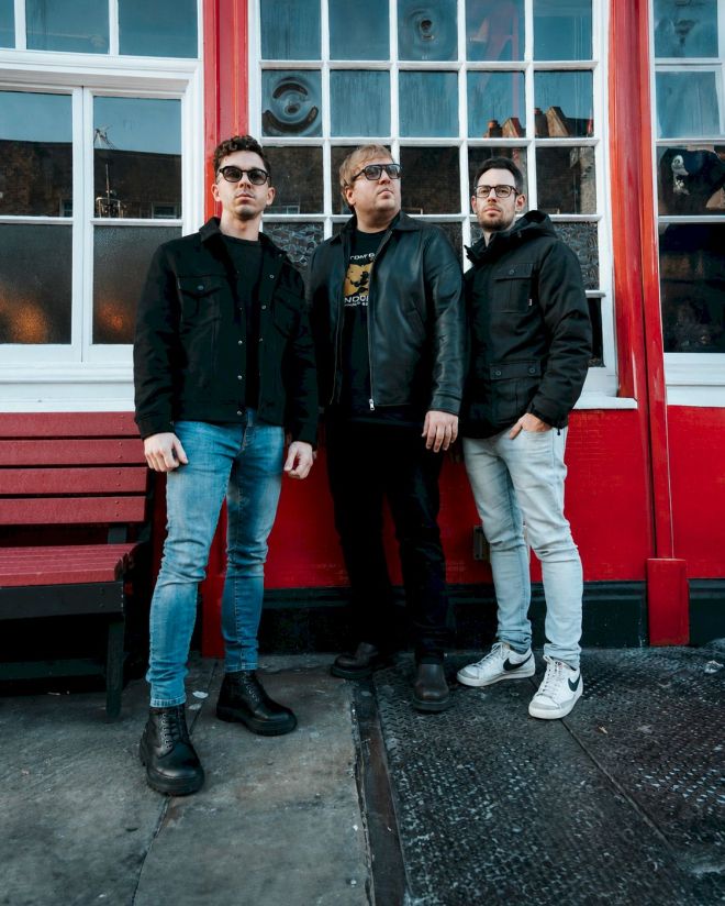Dirty Slippers Wide Open - three white men standing by red wall