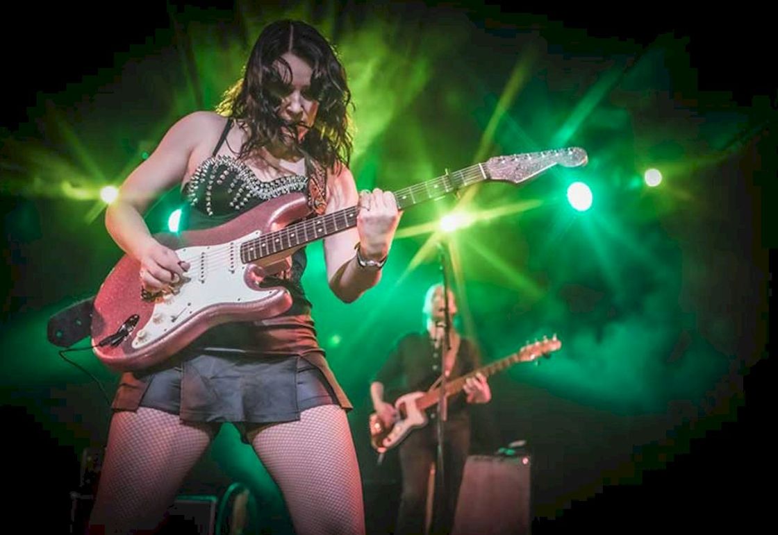 ERJA LYYTINEN 50th Live 2026 Photo Credit © Elsa Wellamo - female guitarist on stage wearing black mini skirt and playing red-body electric guitar