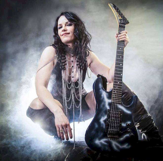ERJA LYYTINEN 50th Birthday Live 2026 Photo Credit © Elsa Wellamo - female guitarist wearing leather-look chaps and holding a black electric guitar